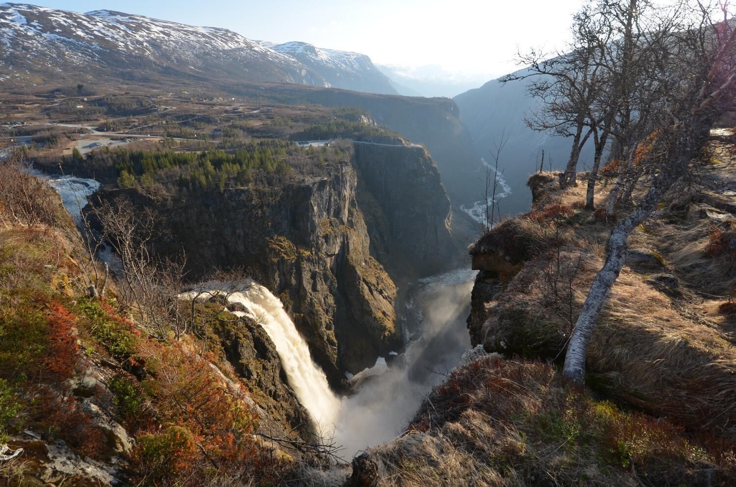 A waterfall cascading down a steep cliff surrounded by rocky terrain and sparse vegetation.