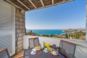 A balcony with a table set for breakfast, overlooking a coastal view. - Villa Narona (Zupa dubrovacka)