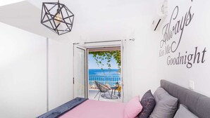 A bedroom with a bed, a sofa, and a view of the sea through an open door. - Villa Laura (Zupa dubrovacka)