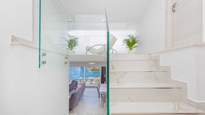 A modern interior with a glass staircase, marble flooring, and a view of an outdoor seating area. - Villa Laura (Zupa dubrovacka)
