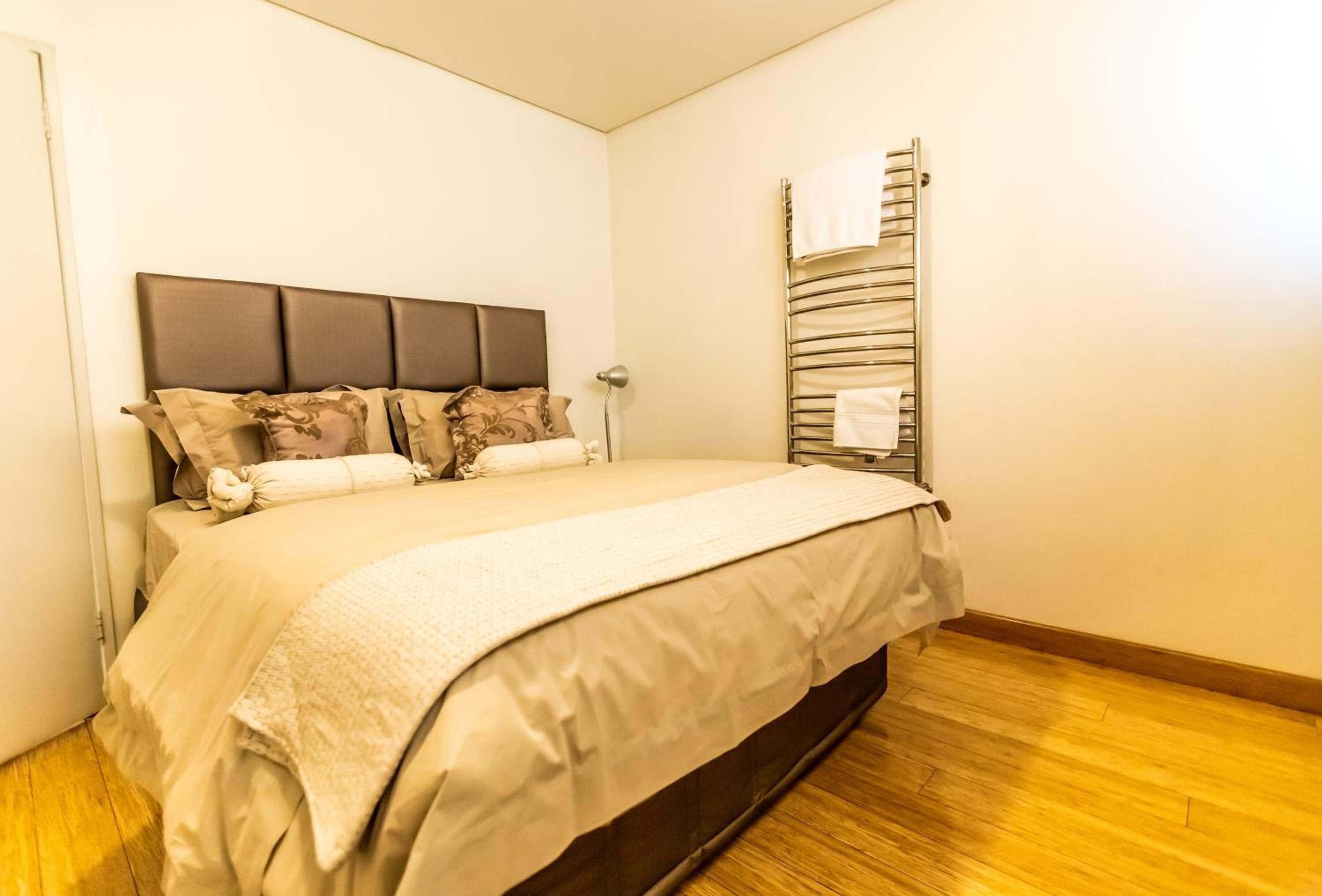A bedroom with a bed, a headboard, a bedside table, and a towel rack.
