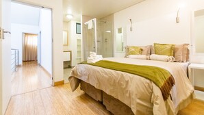 A hotel room with a bed, a bathroom, and a hallway leading to another room. - Inn Green at The Lofts (Secunda)