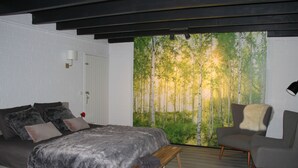 Un dormitorio con cama, una silla, un banco y un mural en la pared con un bosque.
