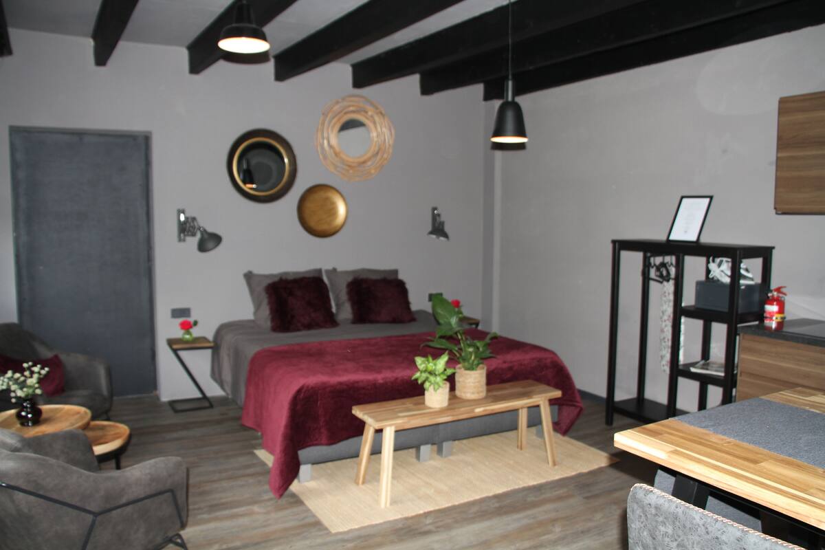 A modern bedroom with a bed, bedside tables, a bench, and a desk.