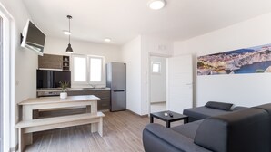 A modern apartment with a kitchen, a dining area, a living room with a sofa, and a large window. - Marojica Apartments (Konavle)