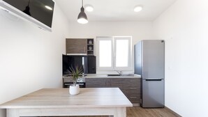 A modern kitchen with a wooden table, a refrigerator, and a window. - Marojica Apartments (Konavle)
