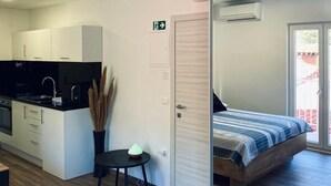 Un appartement moderne comprenant un coin cuisine, un espace repas et une chambre avec une porte coulissante donnant sur un balcon.