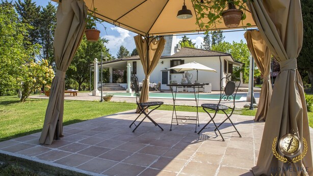 An outdoor patio with a pergola, two chairs, a table, and a pool in the background. - Villa Gemma, revalue wonder of nature near Lake Bolsena (Narni)