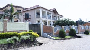 A two-story house with a balcony, a gated entrance, and a water tank. - Green View Apart Hotel (Kigali)
