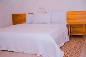 Una cama bien hecha con ropa de cama blanca y cabecera de madera.