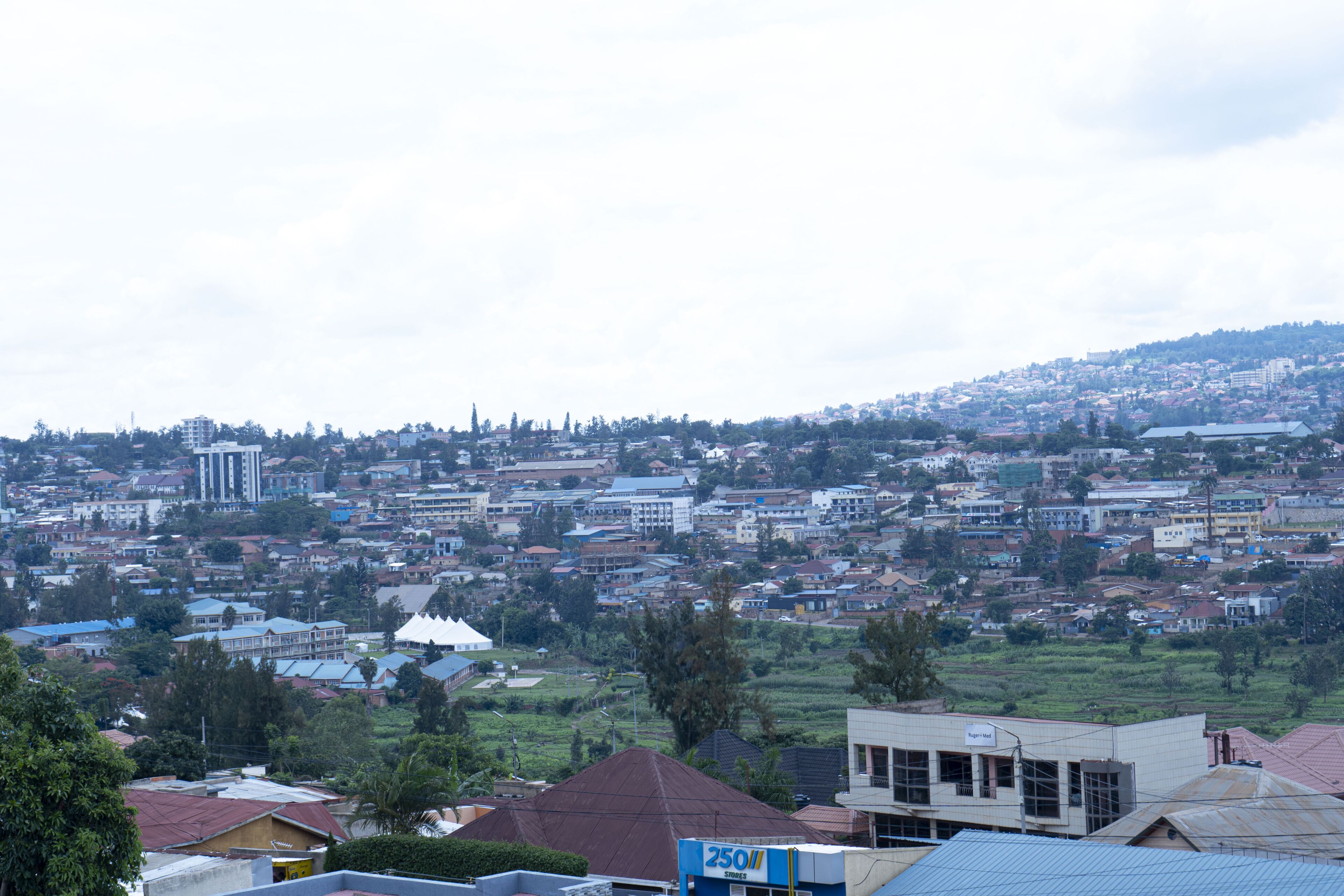A residential area with houses and buildings, a prominent white dome structure, and a hill in the background.