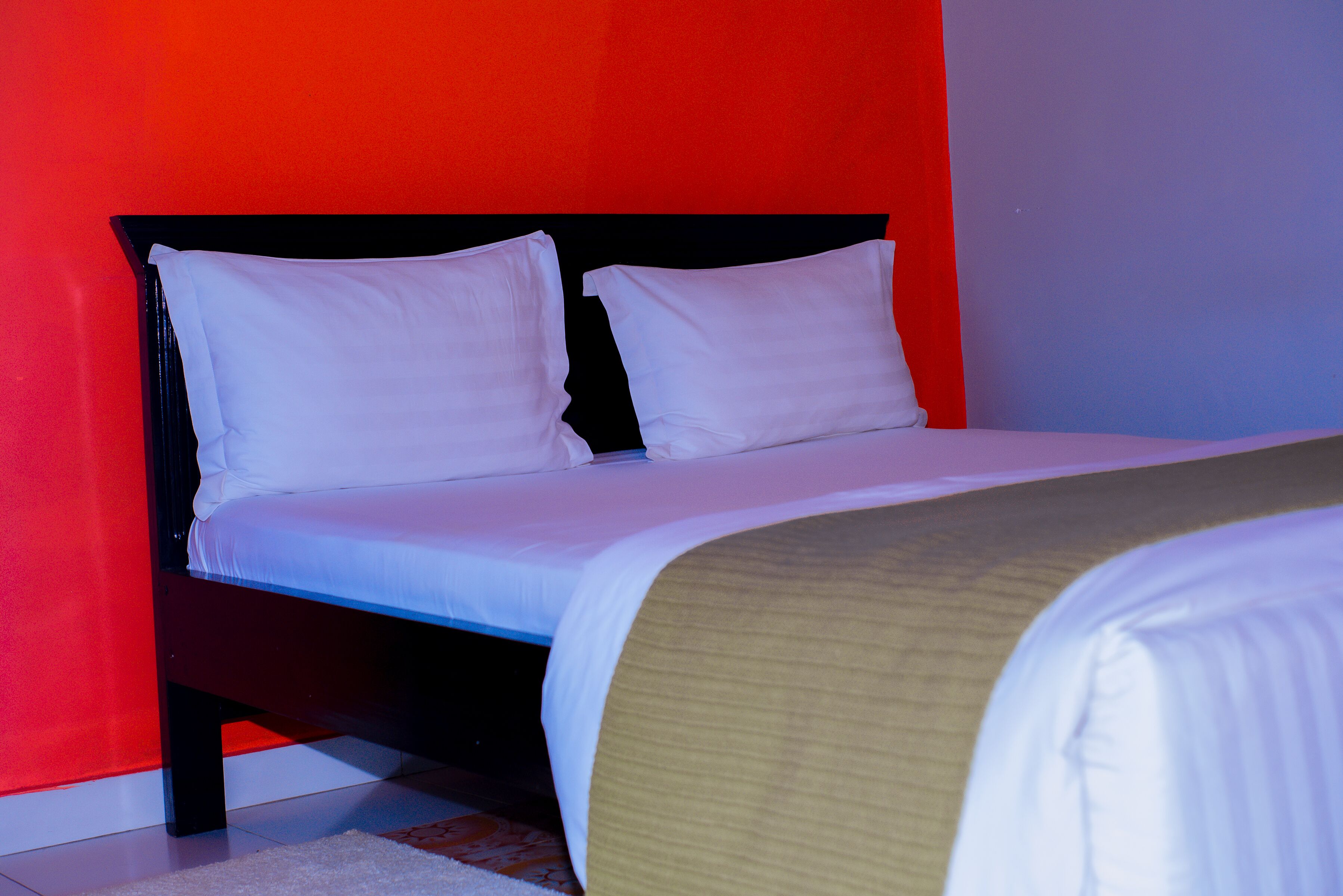 A bed with white bedding in a room with red walls.
