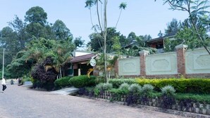 A paved pathway with a brick wall and greenery, leading to a building with a signboard. - Green View Apart Hotel (Kigali)