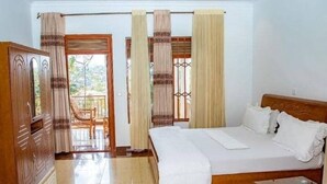 A bedroom with a wooden bed, a glass table, and curtains. - Green View Apart Hotel (Kigali)