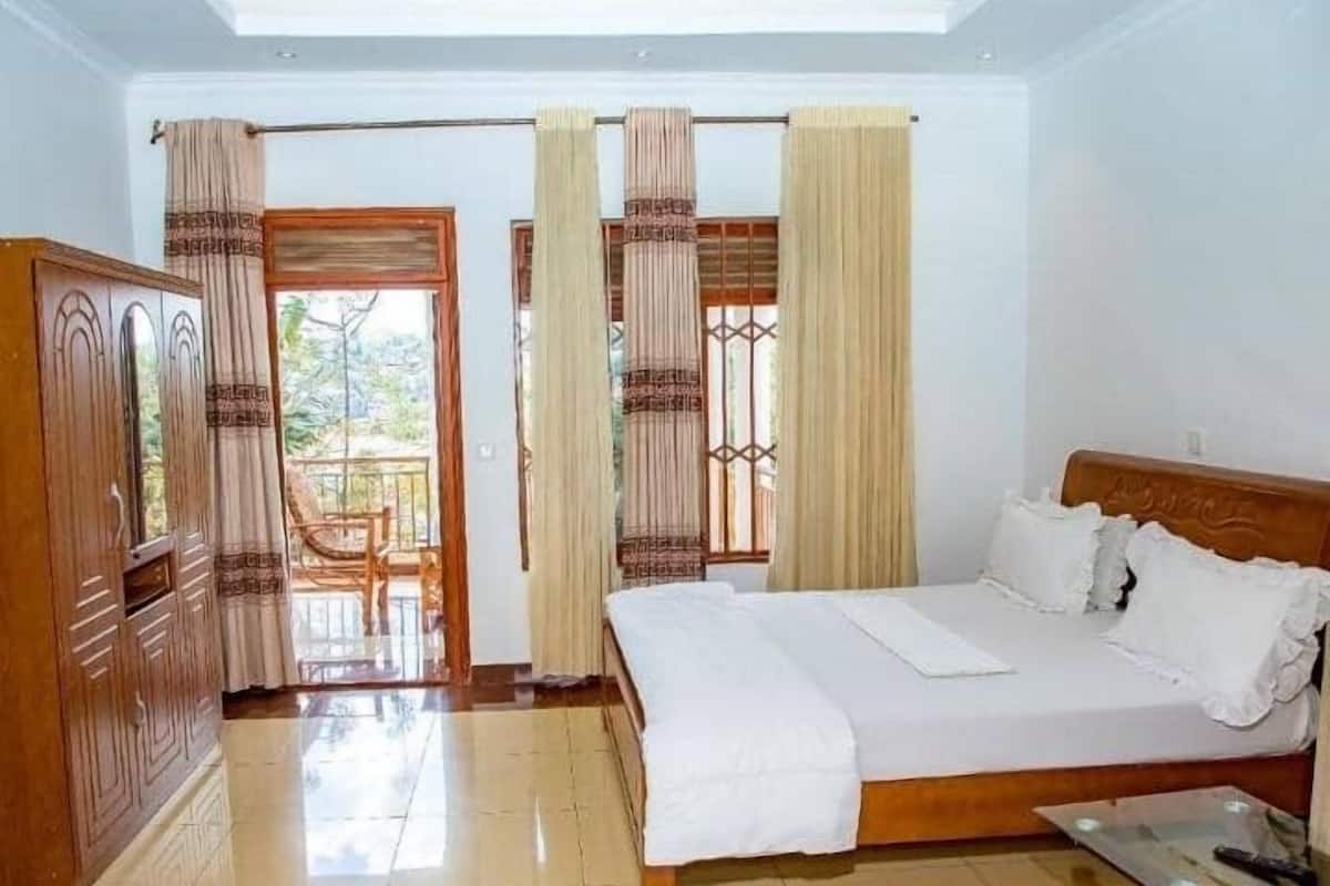 A bedroom with a wooden bed, a glass table, and curtains.