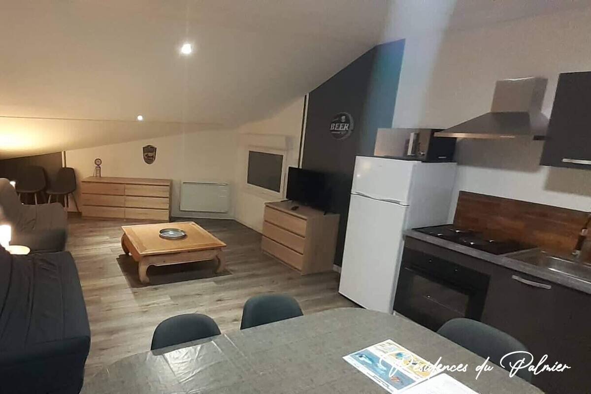 Un espace de vie compact comprenant un canapé, une table à manger, un téléviseur et un coin cuisine.