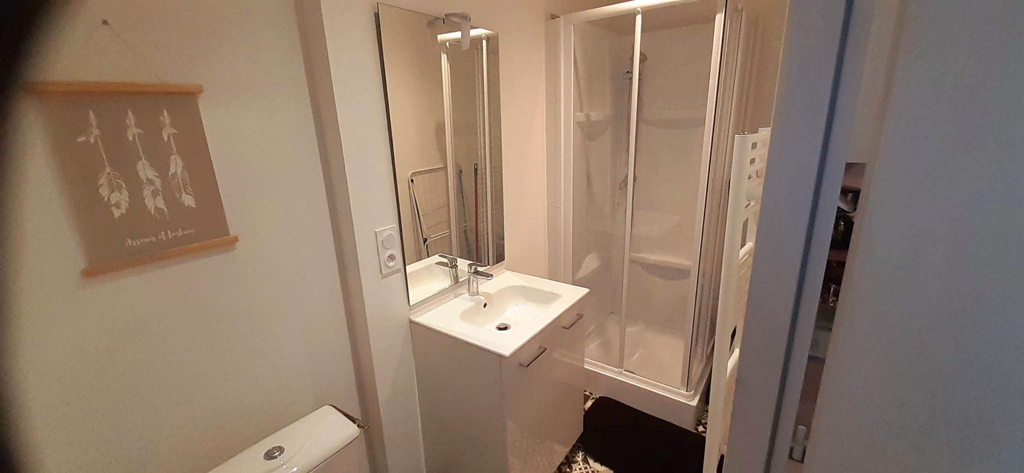 A bathroom with a white sink, mirror, and shower enclosure.