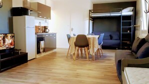 A compact living space with a kitchenette, a dining area, and a bunk bed.