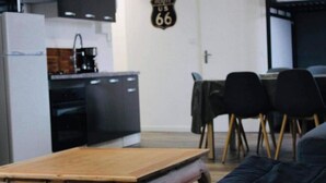 A compact living space with a kitchenette, a dining area with chairs, and a sofa.