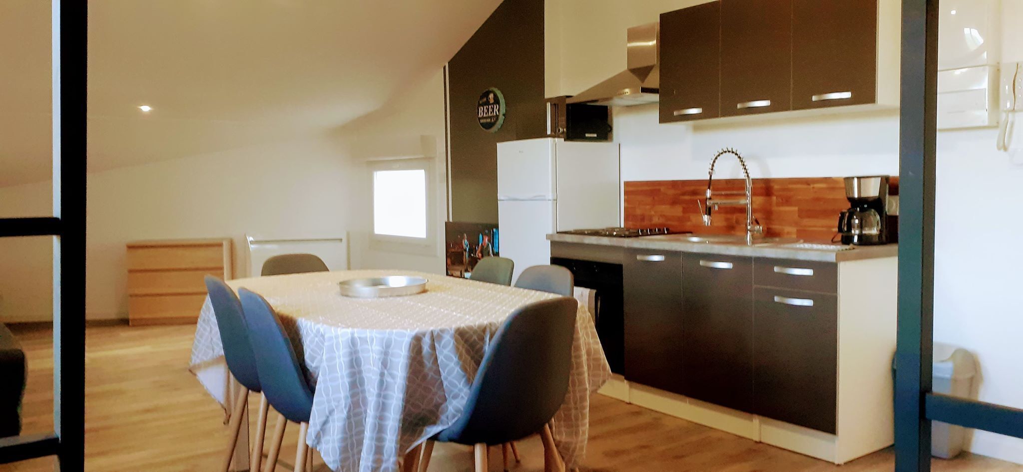 A compact kitchen with a dining area, featuring a refrigerator, stove, and a coffee maker.