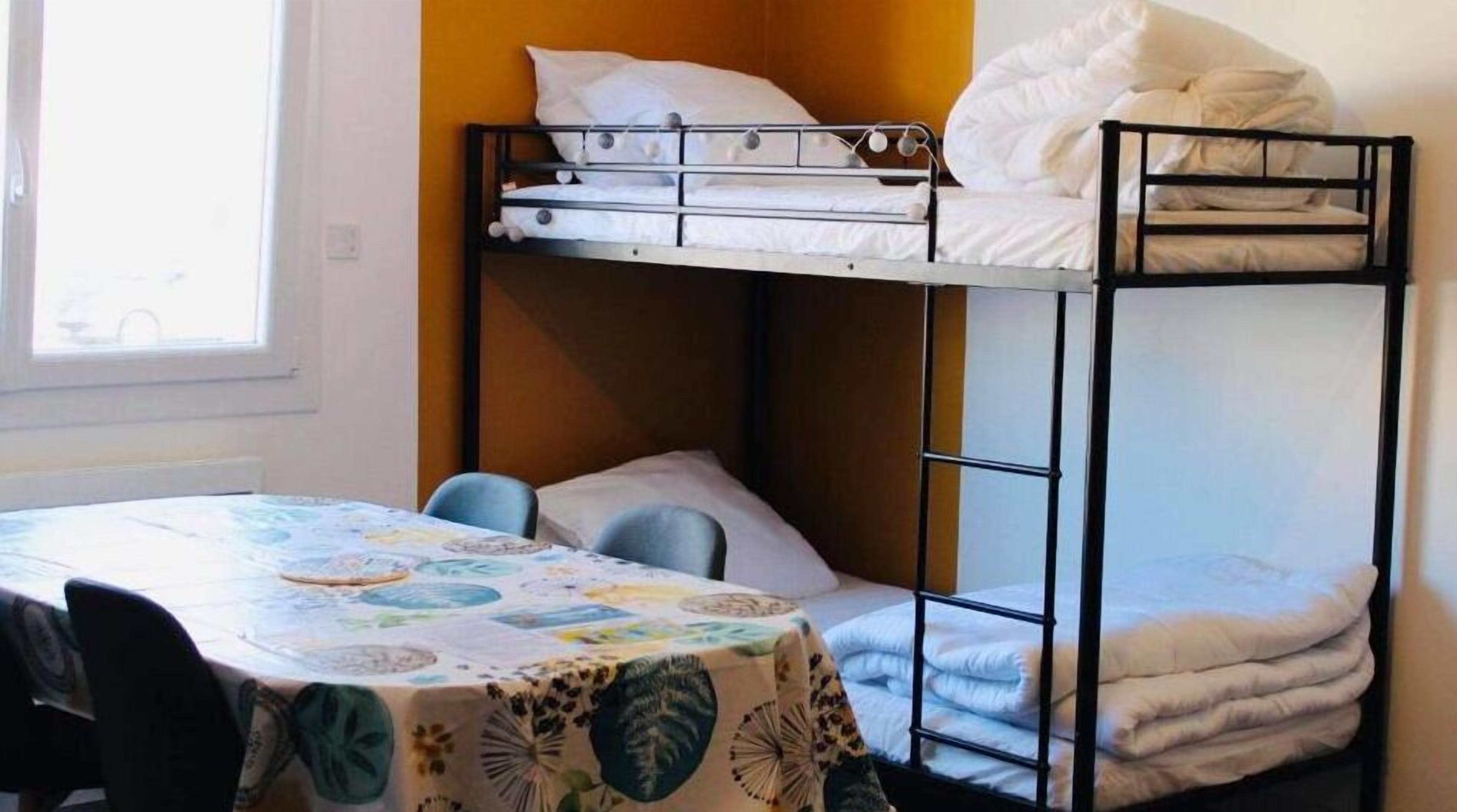 A bunk bed room with a table and chairs, a window, and a door.