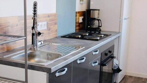 A compact kitchenette with a stainless steel sink, a coffee maker, and a stove.