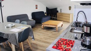 A compact living space with a dining table, sofa, and kitchenette.