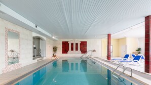 Una piscina interior amb aigua blava cristal·lina, parets de rajola i una zona amb rajoles vermelles i blanques a prop de l'entrada.