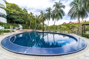 A swimming pool with a tiled edge, surrounded by palm trees and a building with a traditional architectural style in the background. - OYO Home 89794 Uncommon 2br Sri Sayang (George Town)
