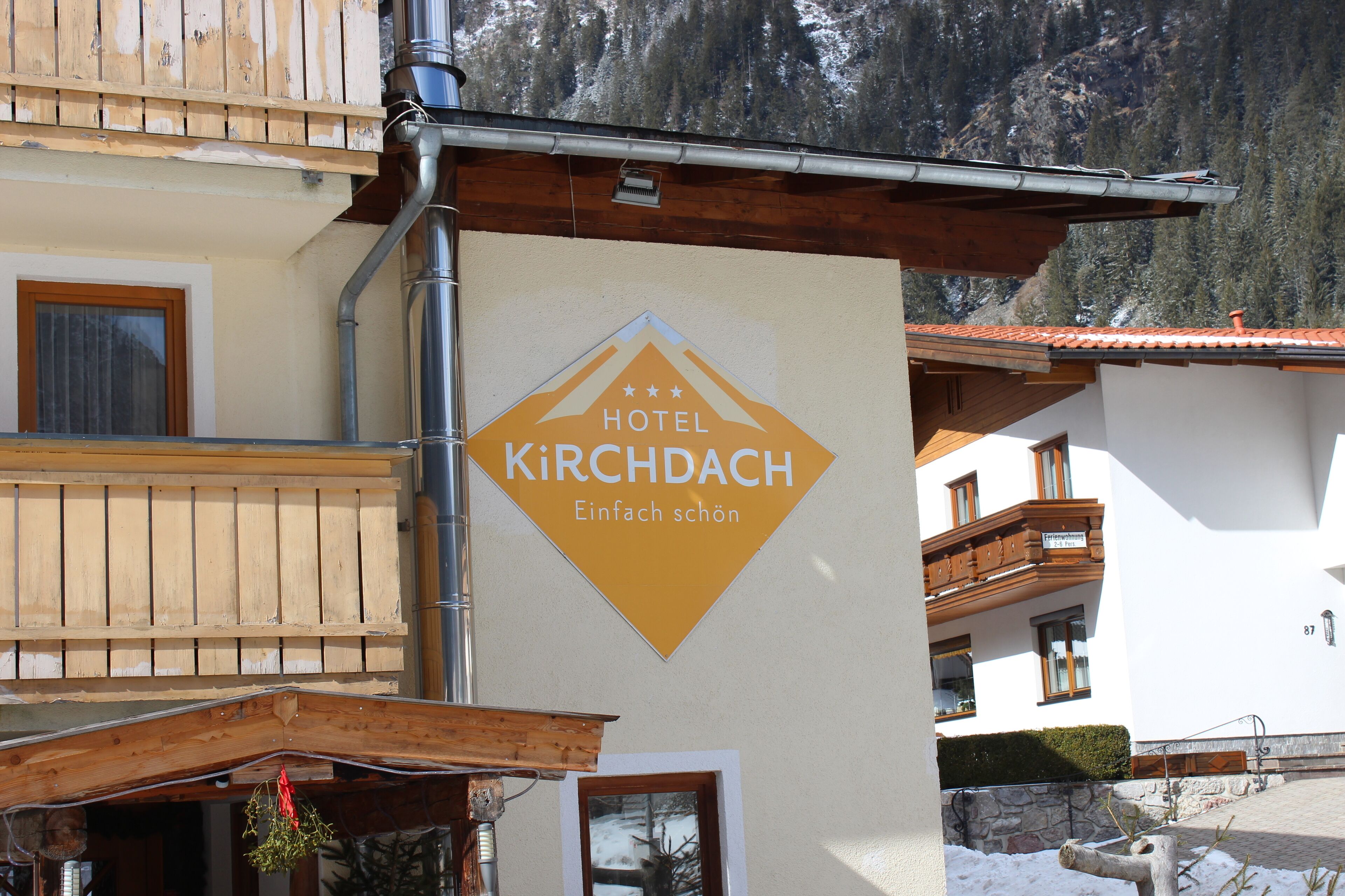 Ein Hotel Schild mit dem Namen „HOTEL KIRCHDACH“ und dem Schriftzug „Einfach schön“ an einer Gebäudefassade.