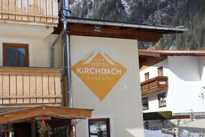 Placa de hotel com o nome 'HOTEL KIRCHDACH' e a frase 'Einfach schön' na fachada de um edifício.