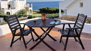 Un patio con una mesa y sillas, una jarrón y un vaso de bebida.
