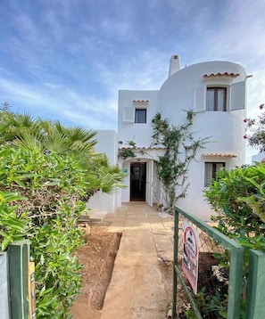 Un bâtiment blanc avec un chemin pavé menant à l’entrée.