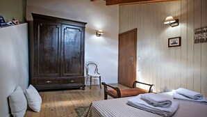 A bedroom with a wooden wardrobe, a bed with folded towels, a chair, and a wall-mounted lamp. - Luxury Family House (Corfu)