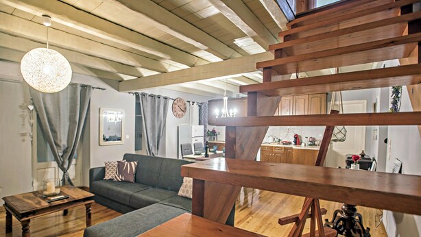 A cozy living room with a wooden ceiling, a sofa, a coffee table, and a dining area with wooden beams. - Luxury Family House (Corfu)