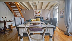A dining area with a wooden staircase, a chandelier, and a table set with chairs. - Luxury Family House (Corfu)
