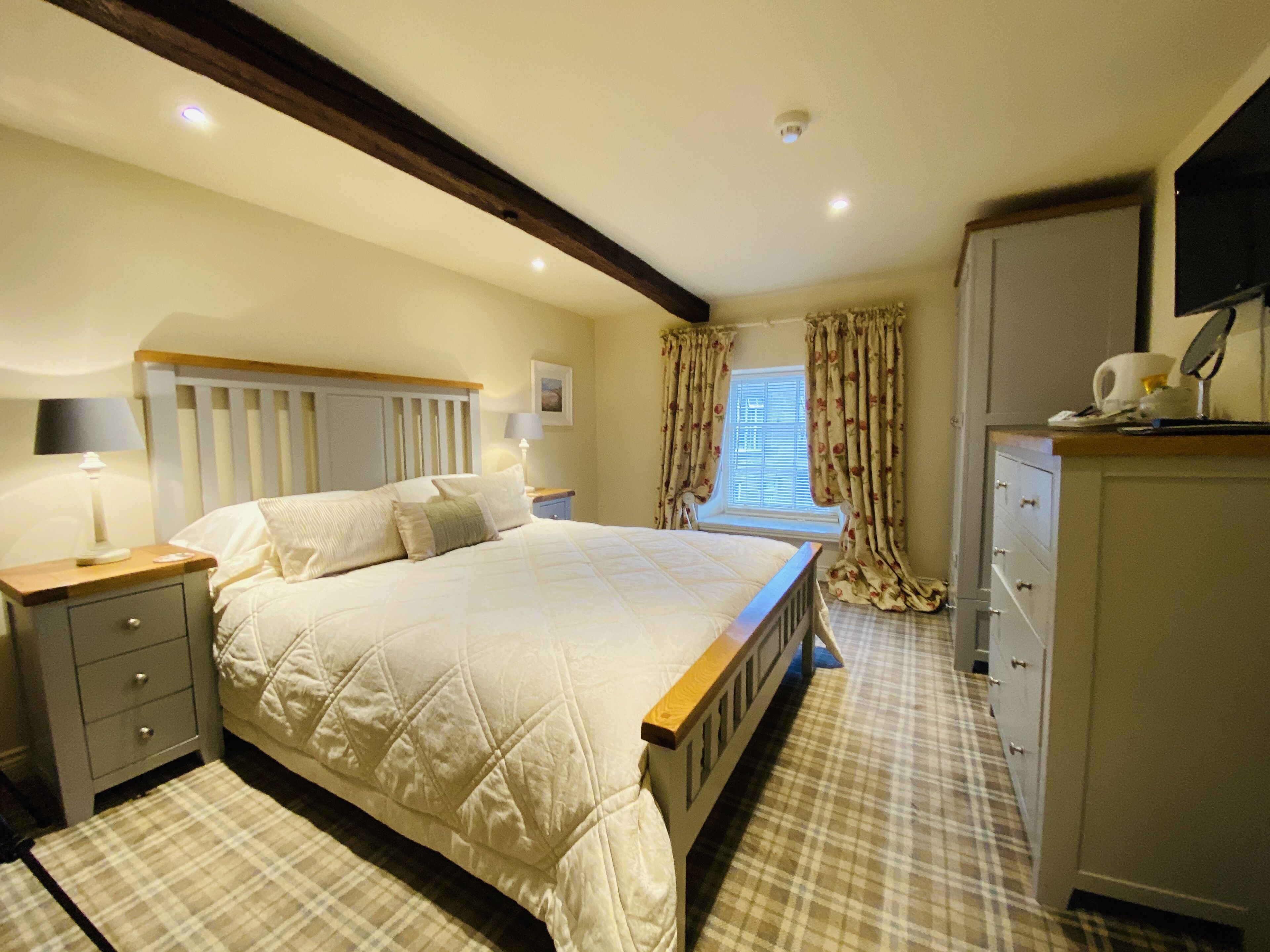 A bedroom with a large bed, bedside tables, a wardrobe, and a window with curtains.