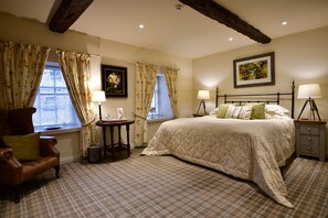 A bedroom with a large bed, two bedside tables with lamps, a chair, a small table with a lamp, and a window with curtains. - The Moon Inn at Stoney Middleton (Hope Valley)