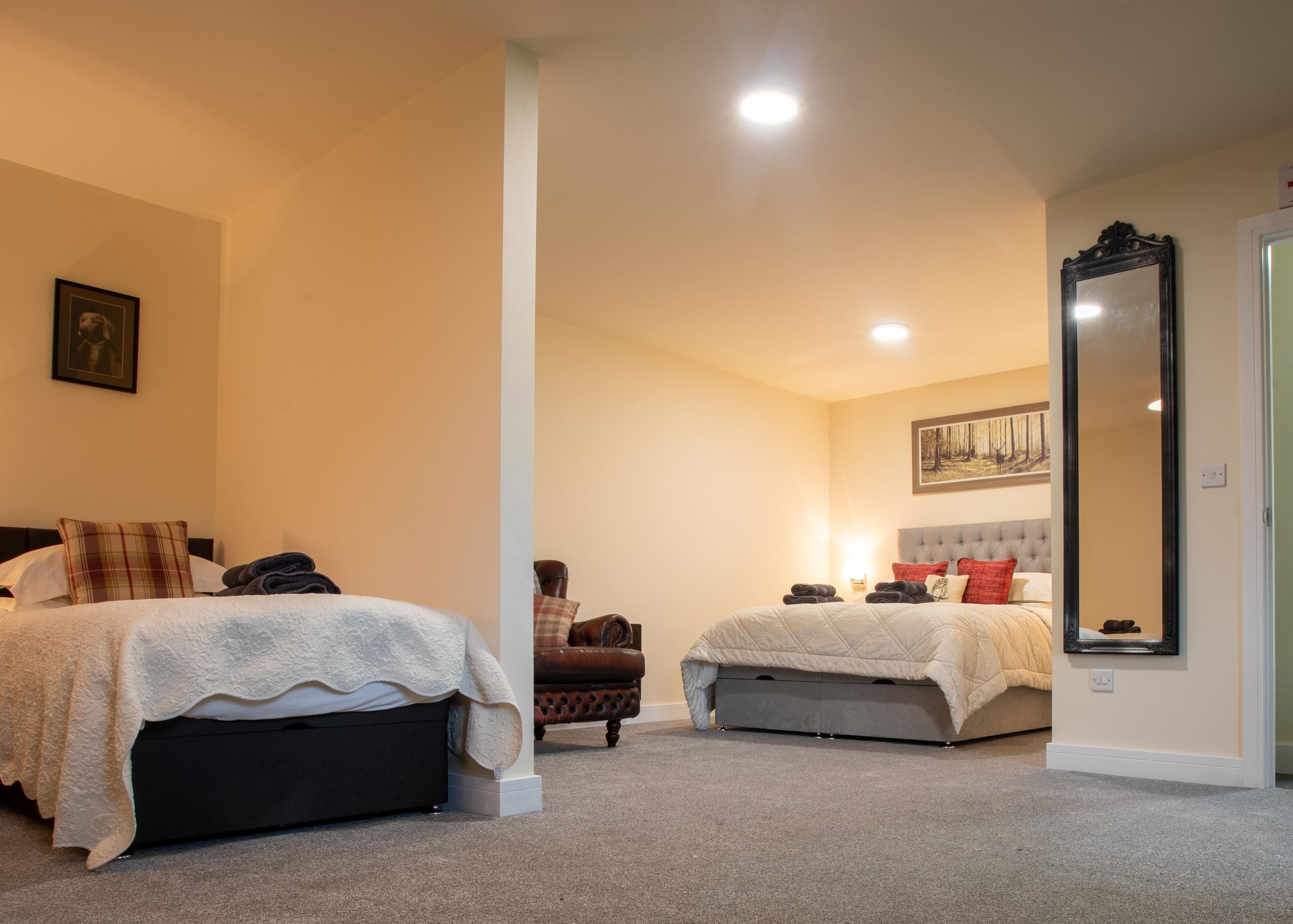 Camera d'albergo con due letti, un grande specchio e un quadro appeso al muro.