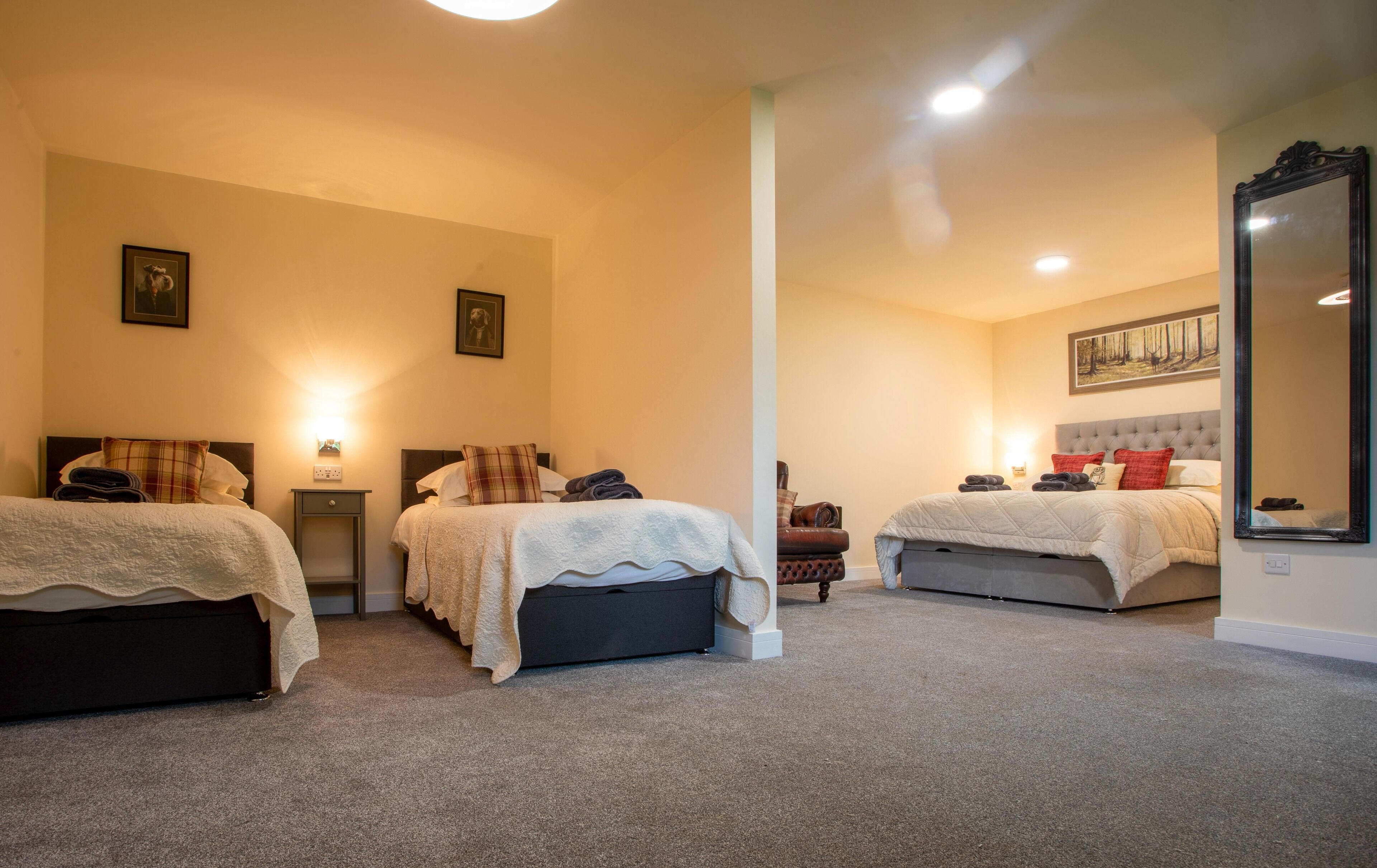 A hotel room with two beds, a large mirror, and a painting on the wall.