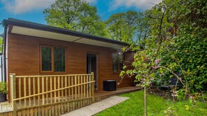 Een houten chalet met een houten terras, een deur en ramen.
