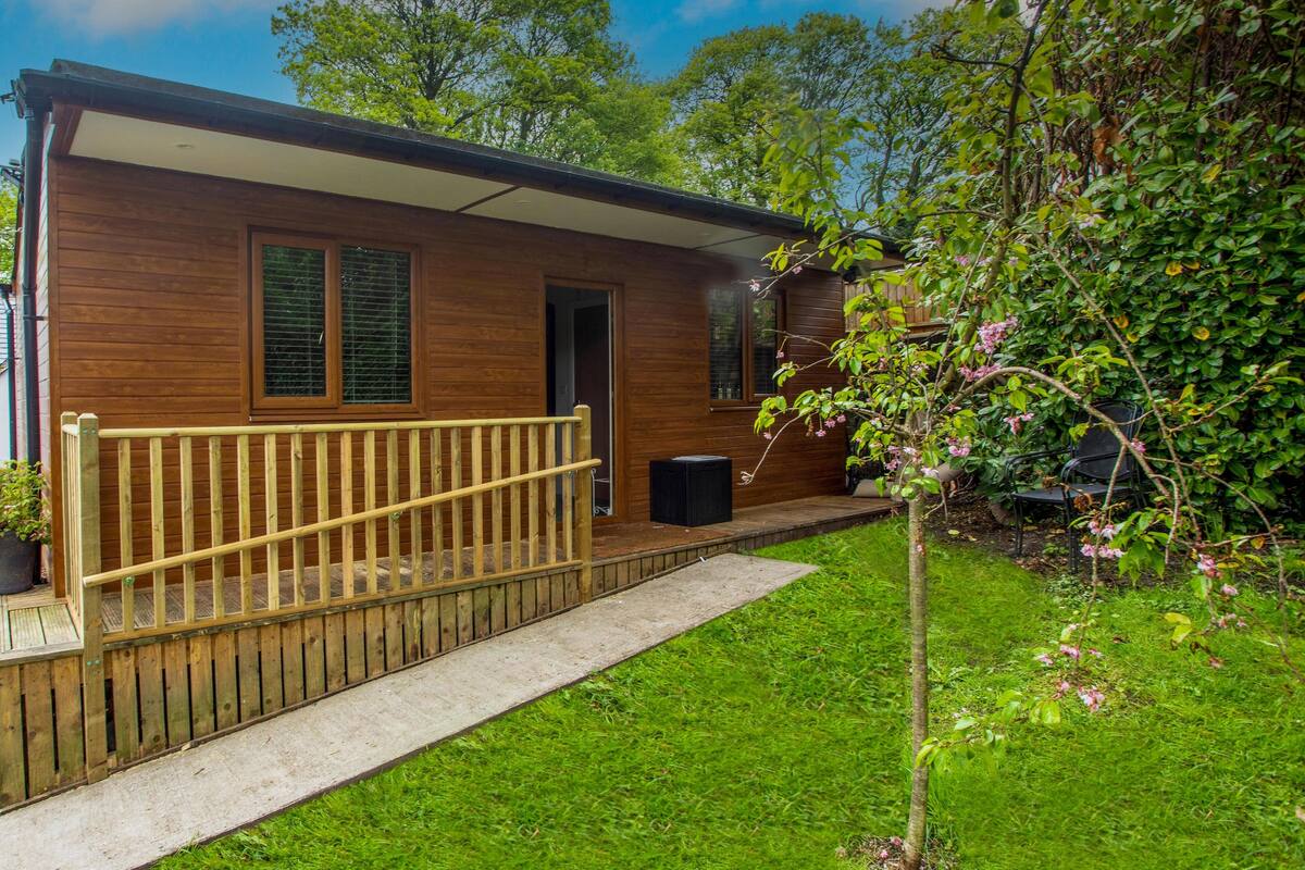 A wooden cabin with a wooden deck, a door, and windows.