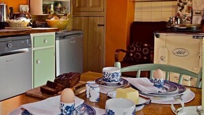 Una cocina con una mesa de comedor preparada para el desayuno, incluyendo huevos, pan y mantequilla.
