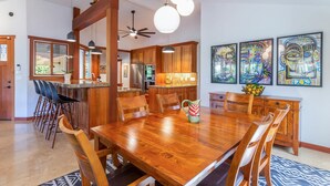 A spacious kitchen with wooden cabinets, a central island, and modern lighting fixtures. - Makana Lei: Recently Upgraded Home w/ Private Pool, AC & Garden Views (Princeville)
