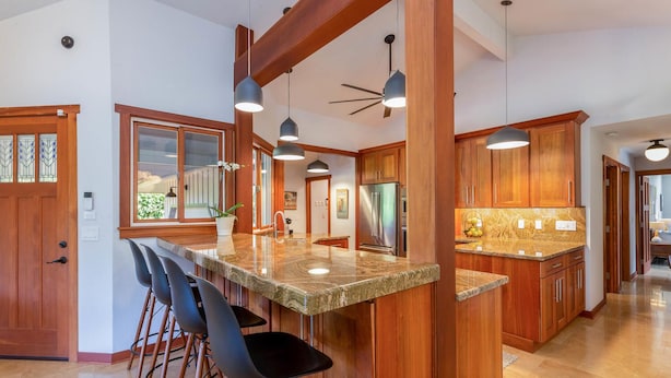 A kitchen with wooden cabinets, a granite countertop, and pendant lighting. - Makana Lei: Recently Upgraded Home w/ Private Pool, AC & Garden Views (Princeville)