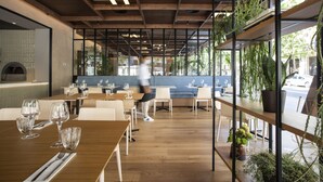 Een interieur met houten tafels, stoelen en hangplanten.