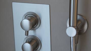 Een modern bedieningspaneel voor de douche, met twee draaiknoppen en een handdouche.
