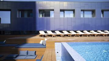 Un área de piscina interior moderna con sillones de descanso y asientos de madera.