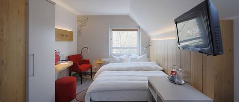 Habitació d'hotel moderna amb llit, escriptori, cadira, televisió i finestra.