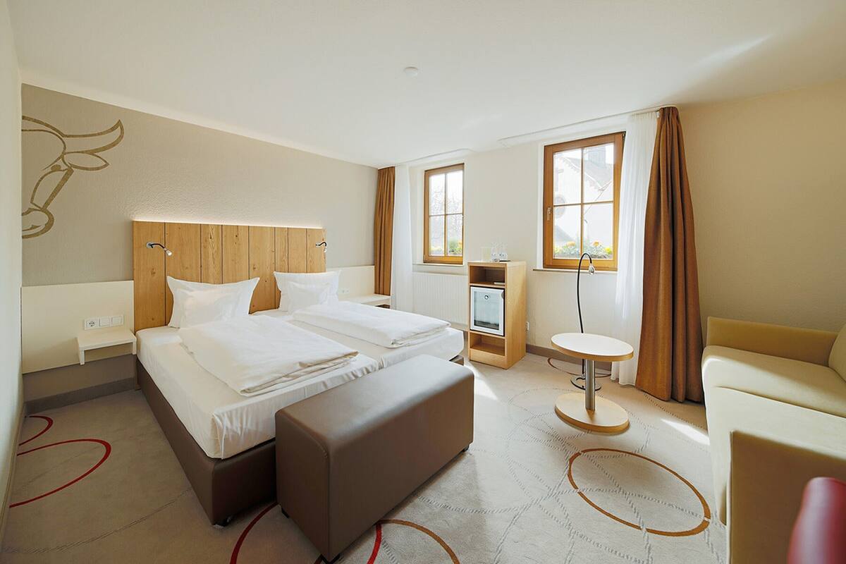 Una habitació d'hotel amb un llit gran, un escriptori, una cadira i una taula petita.
